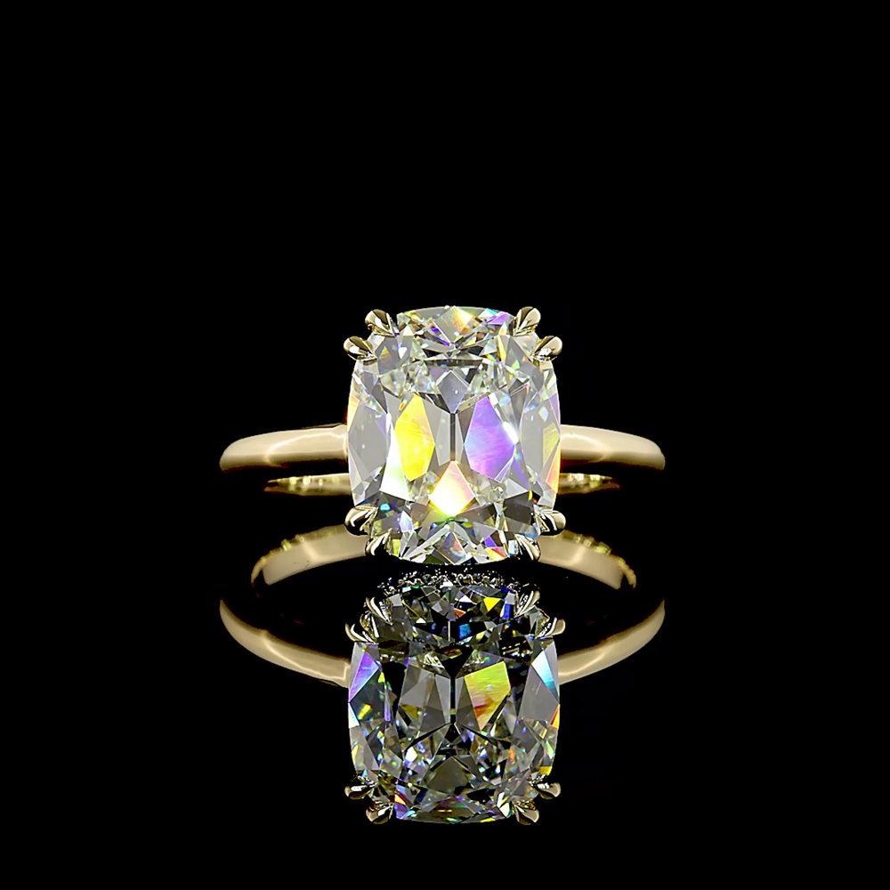 An elongated cushion-cut diamond in a four-prong yellow gold solitaire setting