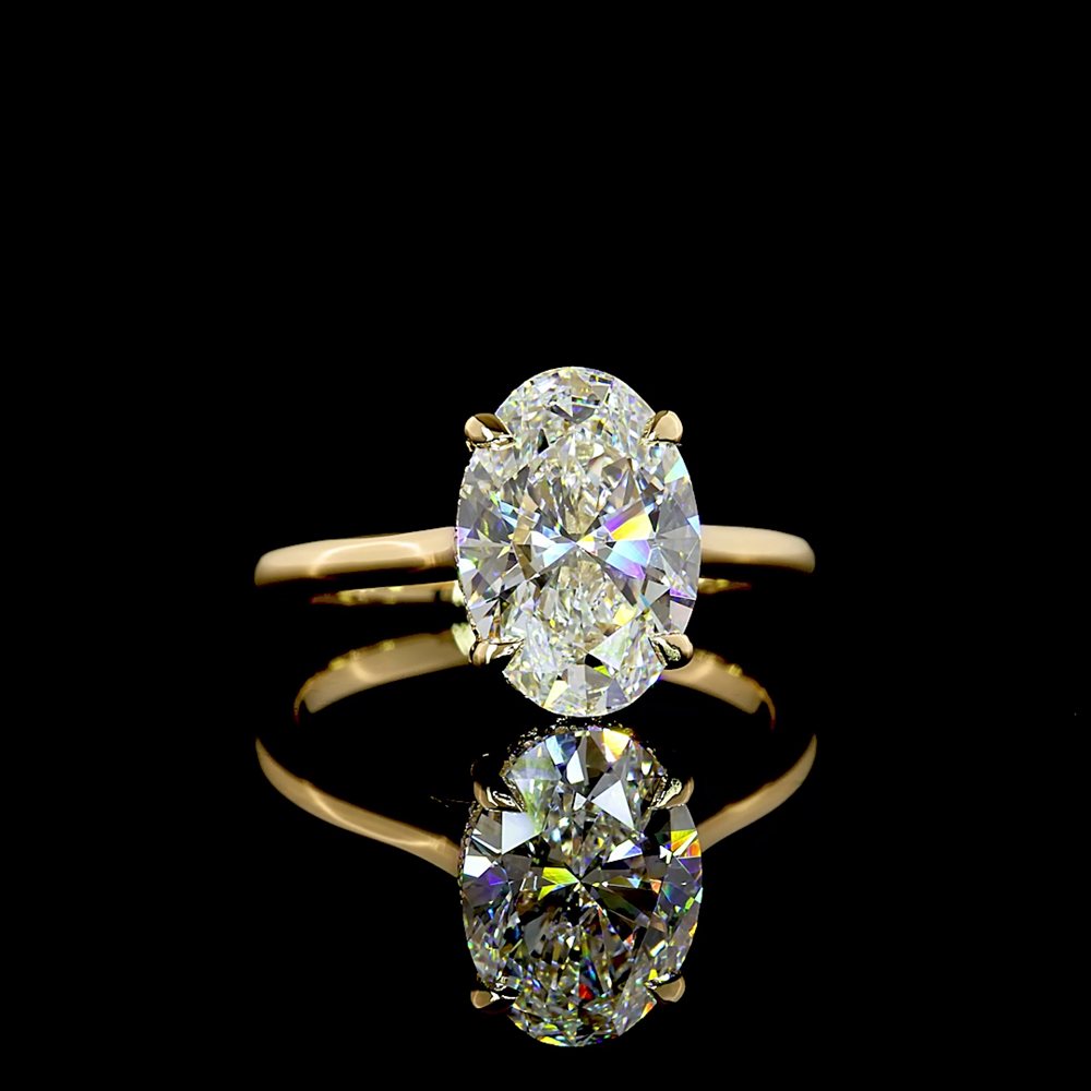 An oval brilliant diamond in a slim yellow gold solitaire setting