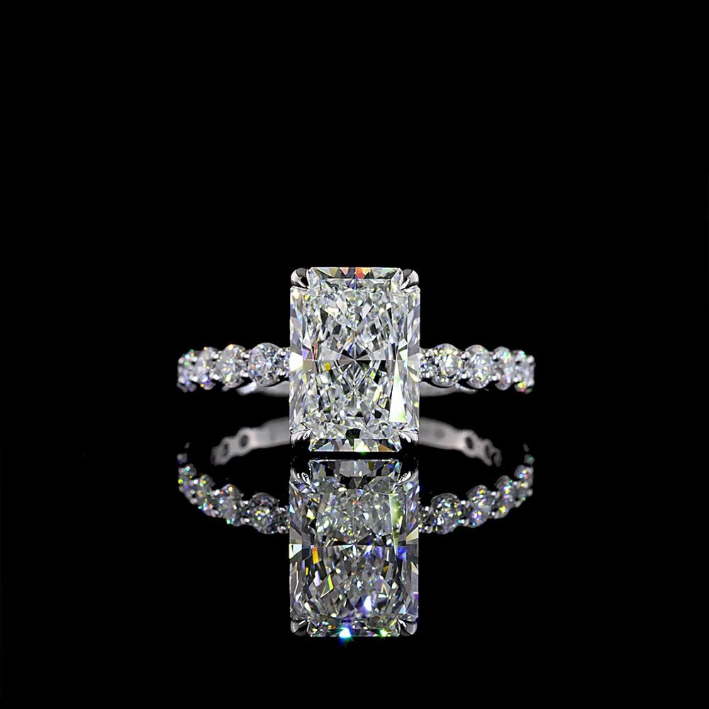An elongated radiant-cut diamond on a white gold band set with round pavé diamonds